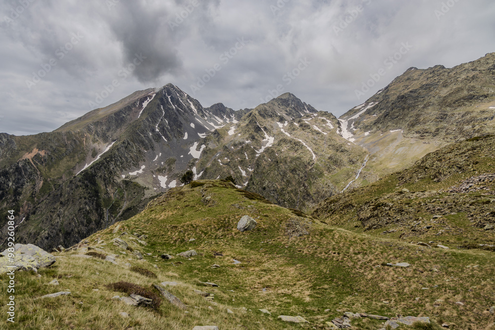 Picturesque landscape on the peak of the mountain with snow and green grass at summer, cloudy in the mountains of Andorra, Arinsal Picturesque landscape on the peak of the mountain with snow and green grass at summer, cloudy in the mountains of Andorra, Arinsal