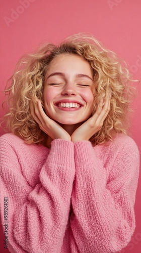 Radiant joy captured in a monochromatic pink portrait: curly blonde hair frames a beaming smile, eyes closed in blissful contentment, hands gently cradling face.