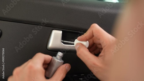 Mechanic male carefully fixing scratch on car door handle with touch-up paint, showing skill and focus in automotive maintenance. Detailer apply retouching paint to scratched car door handle.