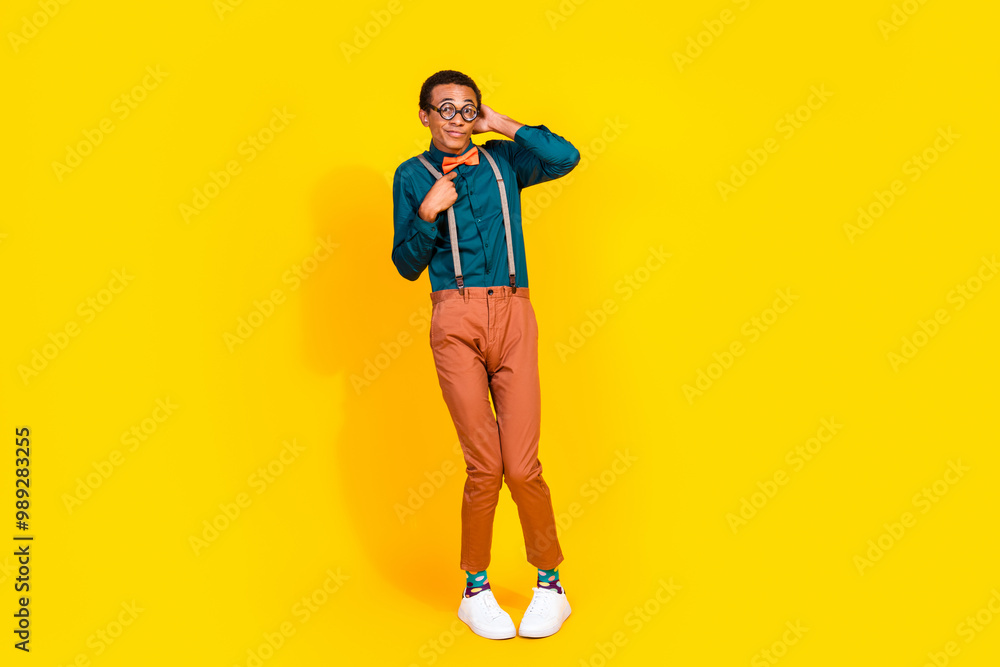 Photo of worried guy touch head suspenders feel unsure shy wear trend glamour clothes isolated yellow color background Photo of worried guy touch head suspenders feel unsure shy wear trend glamour clothes isolated yellow color background