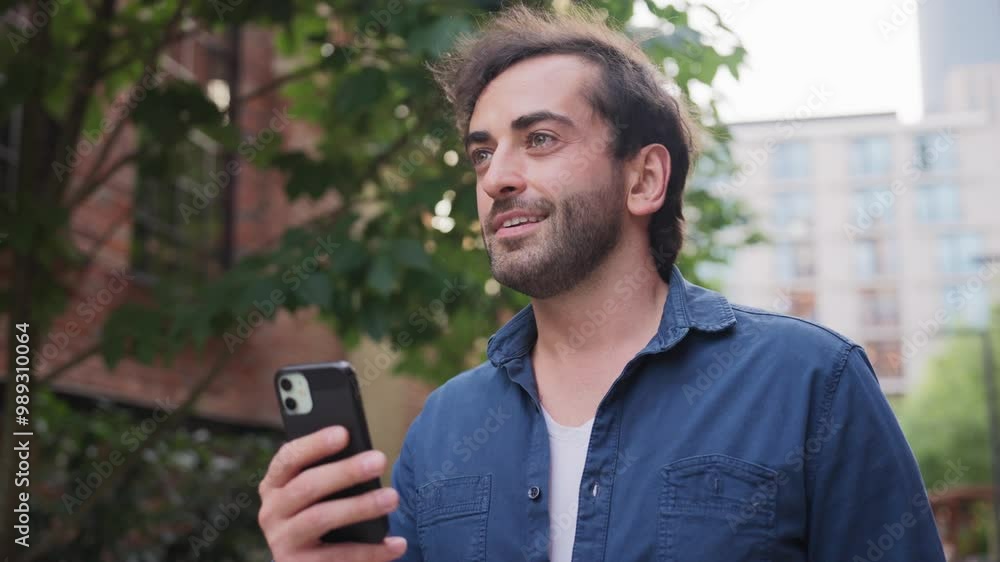 Handsome Caucasian man walking in city and using his smartphone. Looking at screen while searching for correct location. Using online maps. Checking correct direction in application. Handsome Caucasian man walking in city and using his smartphone. Looking at screen while searching for correct location. Using online maps. Checking correct direction in application.