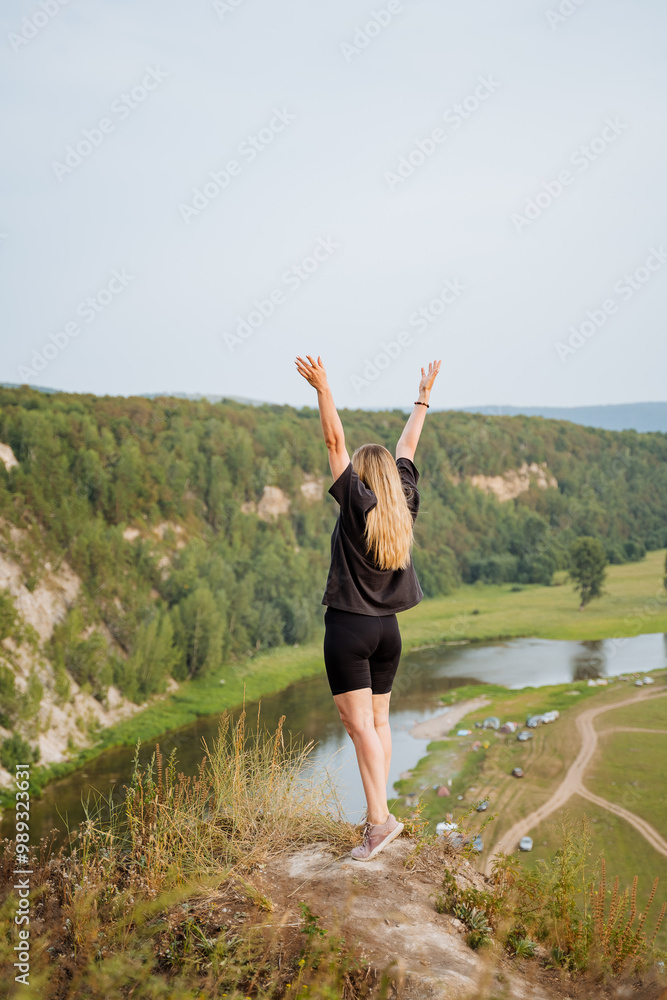 A joyful woman triumphantly stands atop a picturesque hill, her arms raised high in celebration, fully embracing her happiness amidst a stunning natural backdrop and an expansive blue sky A joyful woman triumphantly stands atop a picturesque hill, her arms raised high in celebration, fully embracing her happiness amidst a stunning natural backdrop and an expansive blue sky