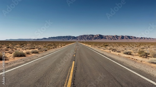 A long, open road extending through a dry landscape beneath a bright blue sky, perfect for travel and adventure themes.