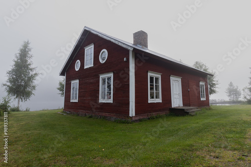 Swedish red stuga enveloped in mist. The morning mist creates a small, tranquil world, with the red house drawing attention