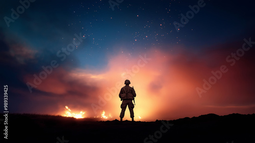 A lone soldier stands silhouetted in front of an intense battlefield scene, illuminated by fire and stars in the night sky.