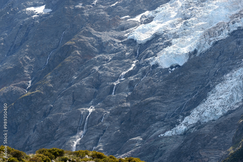 A small cascade from the top of mountain glaciers flowing along the rock cliff of mountain ranges in the Mount Cook National Park, South Island, New Zealand. A small cascade from the top of mountain glaciers flowing along the rock cliff of mountain ranges in the Mount Cook National Park, South Island, New Zealand.