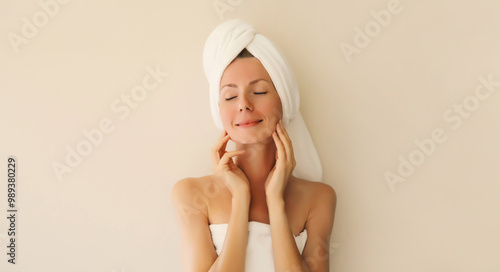 Beauty portrait of happy smiling young caucasian woman touches her clean skin while drying wet hair