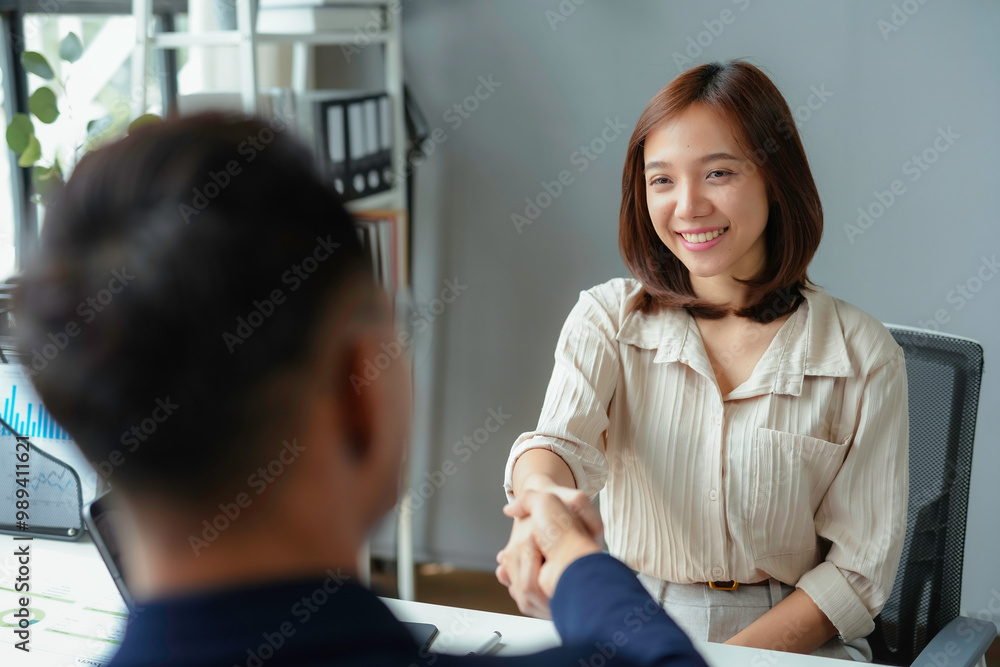 Smiling asian businesswoman shaking hands with a businessman at the end of a successful job interview