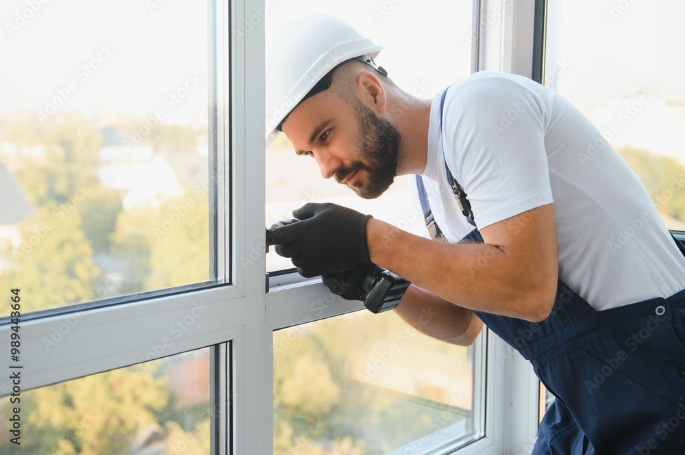 handyman adjusting white pvc plastic window indoors. worker using screwdriver to repair upvc window. homework maintenance handyman adjusting white pvc plastic window indoors. worker using screwdriver to repair upvc window. homework maintenance