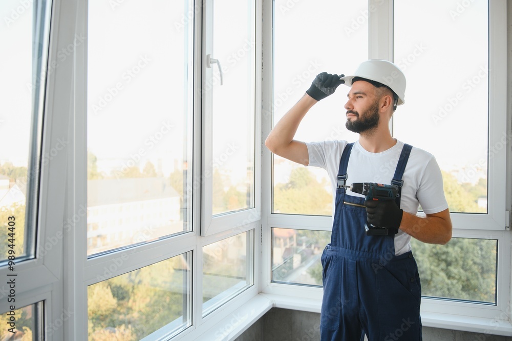 Construction worker installing window in house Construction worker installing window in house