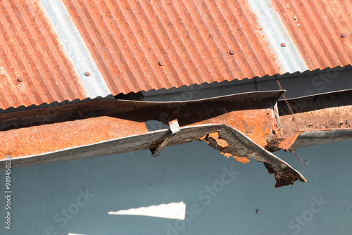 damaged rusty rain gutter under rusty old zinc roof