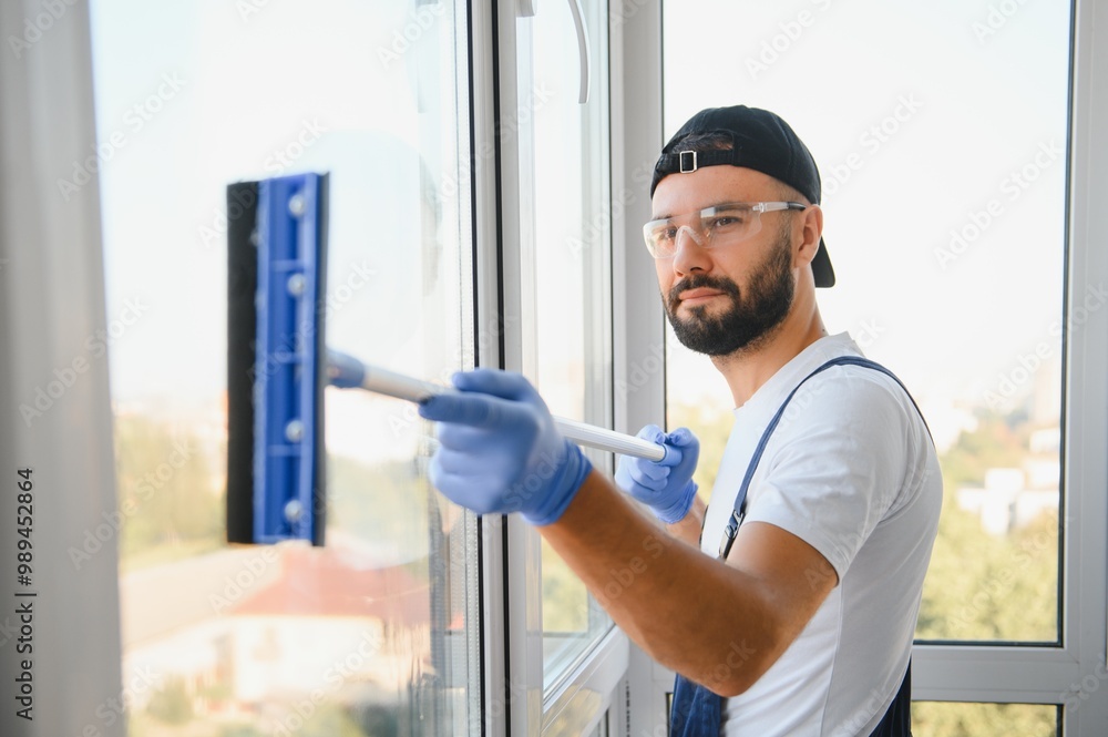 An employee of a professional cleaning service washes the glass of the windows of the building An employee of a professional cleaning service washes the glass of the windows of the building