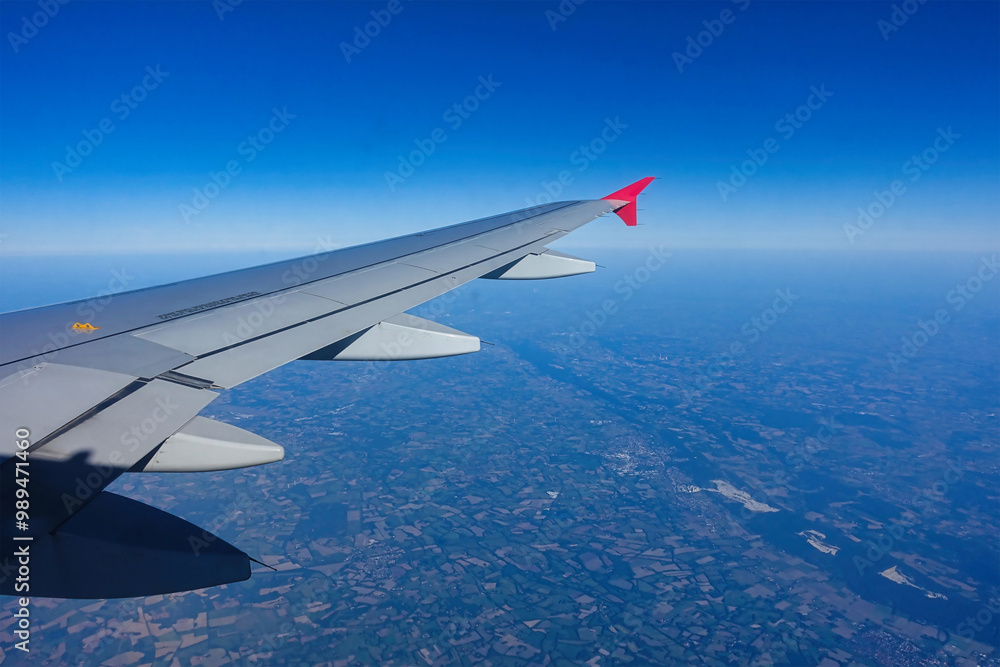 View of the airplane wing in clear weather with blue sky and sunshine.. View of the airplane wing in clear weather with blue sky and sunshine..