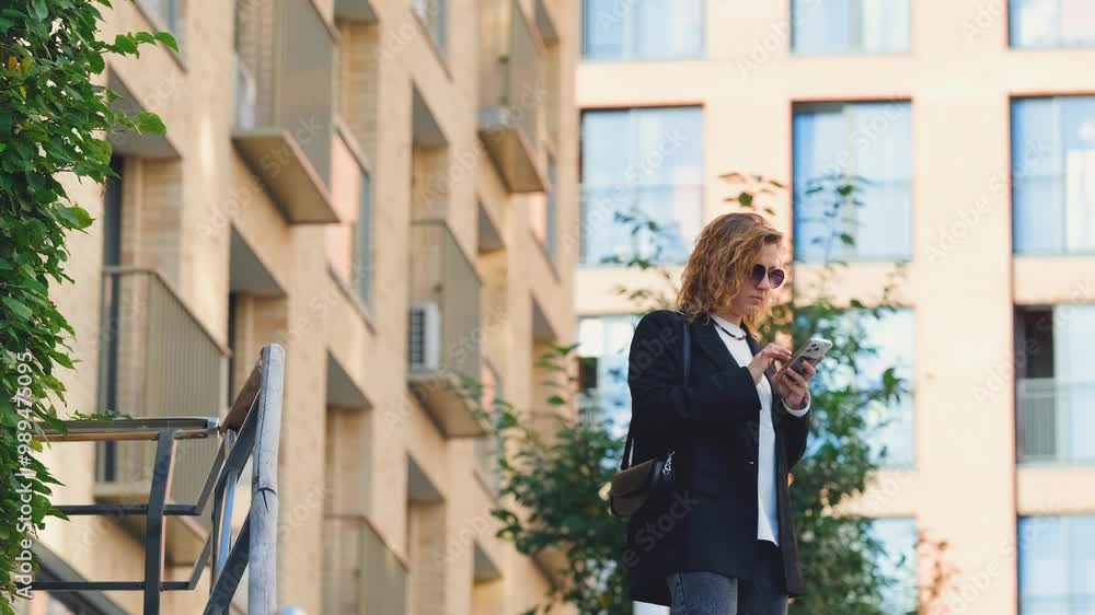 Caucasian woman with curly hair using her mobile phone outdoors. Communication technology and modern lifestyle concept Caucasian woman with curly hair using her mobile phone outdoors. Communication technology and modern lifestyle concept