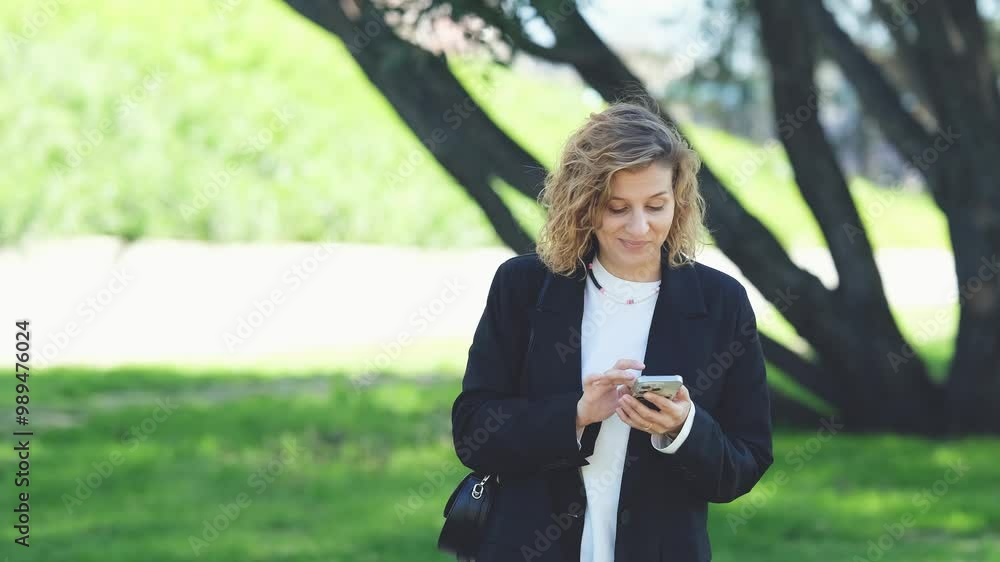 Caucasian woman with curly hair using her mobile phone outdoors. Close-up. Communication technology and modern lifestyle concept Caucasian woman with curly hair using her mobile phone outdoors. Close-up. Communication technology and modern lifestyle concept