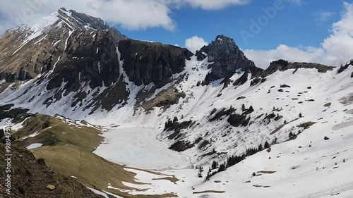 Hd video of Lessy lake in spring, with mountains covered in snow and ice recovering the alpine lake in Haute Savoie, in massif of Bornes Aravis photo