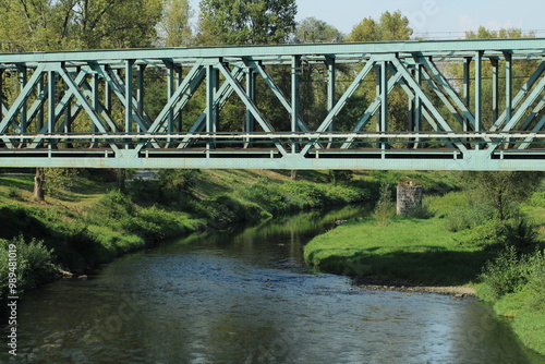 Green metal train bridge across the river 