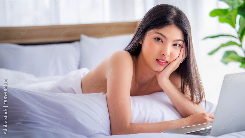 Pretty attractive sensuality young Asian woman wearing red bra and using laptop, laying on the white bed at bedroom in the morning Pretty attractive sensuality young Asian woman wearing red bra and using laptop, laying on the white bed at bedroom in the morning