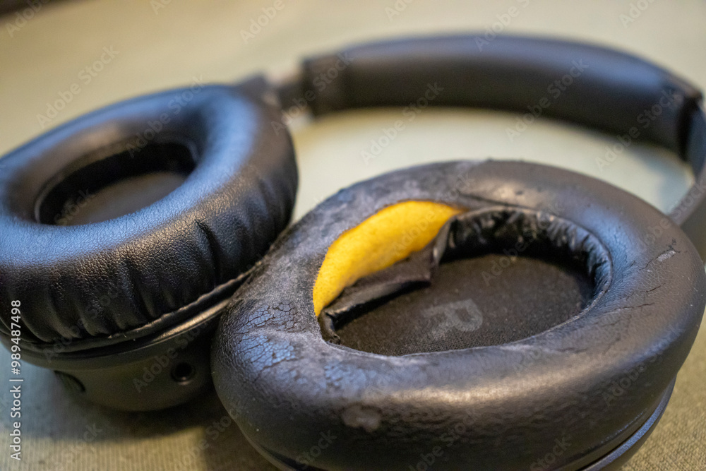 Close-up of worn-out black headphones showing cracked cushioning. Ideal for articles on technology, audio equipment, or product reviews. Close-up of worn-out black headphones showing cracked cushioning. Ideal for articles on technology, audio equipment, or product reviews.