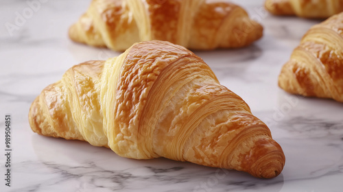 Three golden croissants on a marble countertop