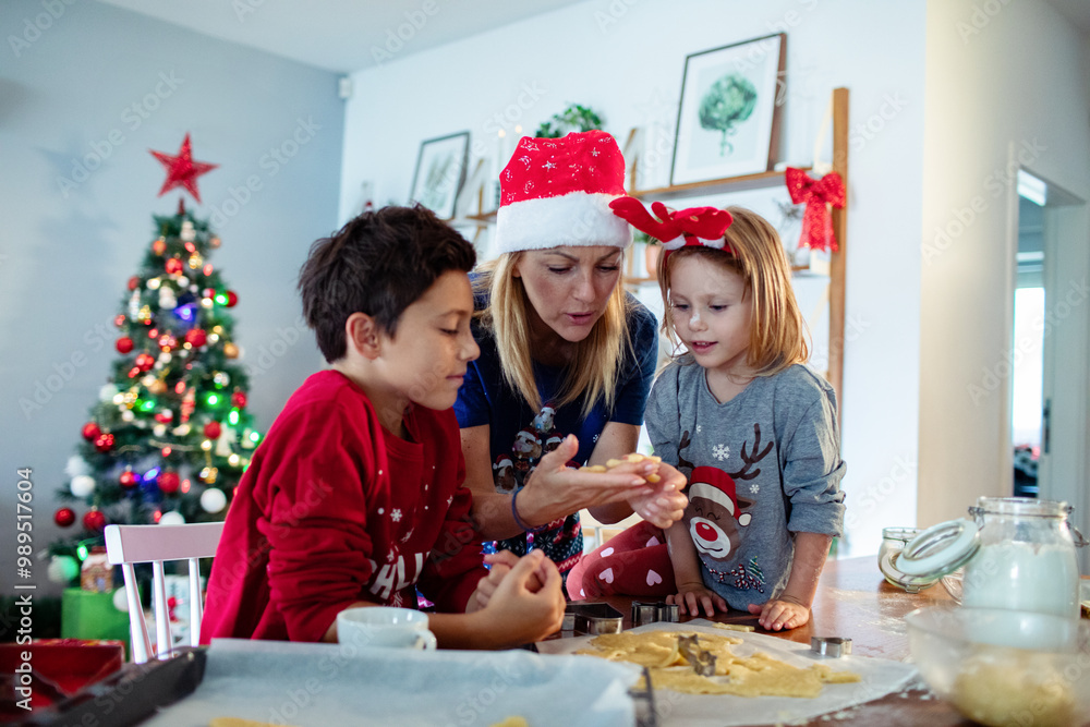 Family baking Christmas cookies together in festive kitchen with Christmas tree Family baking Christmas cookies together in festive kitchen with Christmas tree