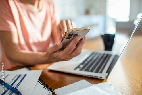 Senior woman managing finances on laptop at home photo