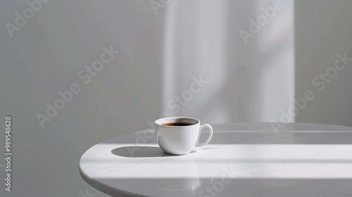 Single white coffee cup filled with black coffee sits on round marble table. soft natural light casts gentle shadows, creating serene and minimalist atmosphere.