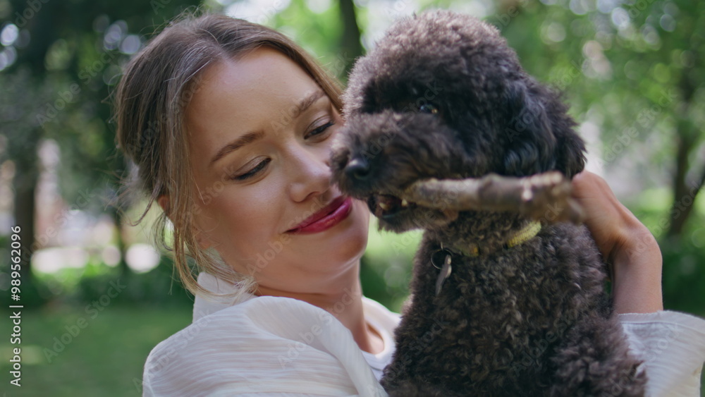 Smiling woman holding poodle on sunny nature closeup. Joyful girl cuddling dog Smiling woman holding poodle on sunny nature closeup. Joyful girl cuddling dog