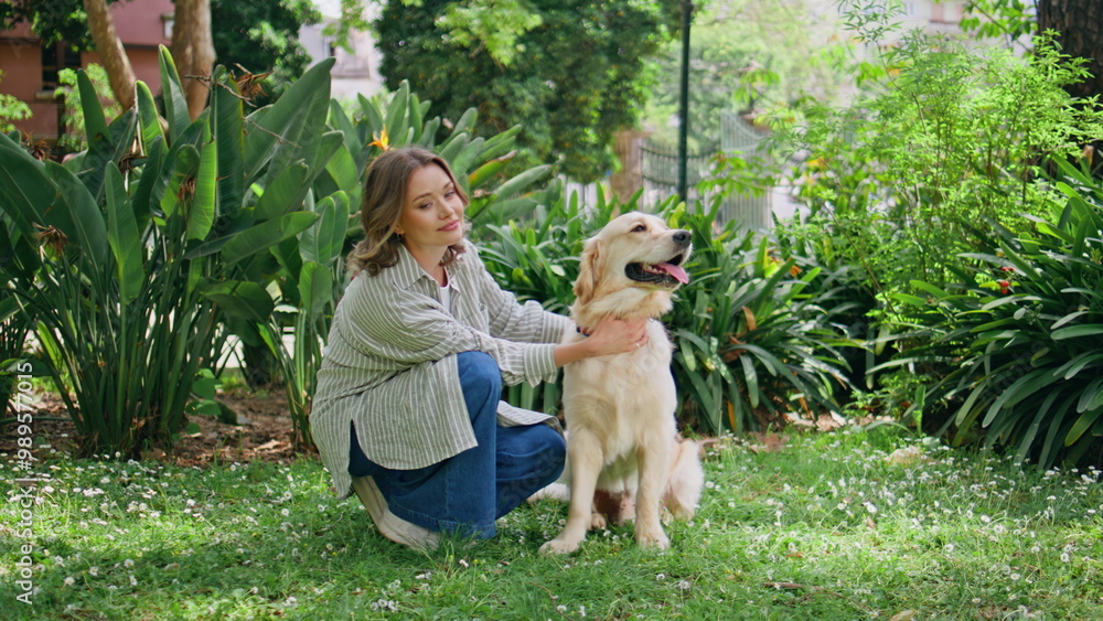 Obraz premium Young woman sitting retriever in green park closeup. Relaxed girl kneeling dog 