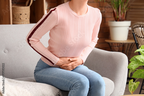 Fotografija Young woman suffering from stomach ache on sofa at home