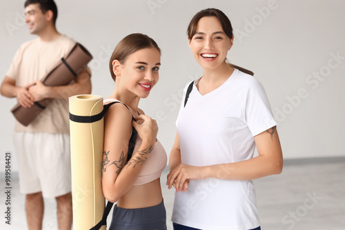 Sporty young women with yoga mats in gym