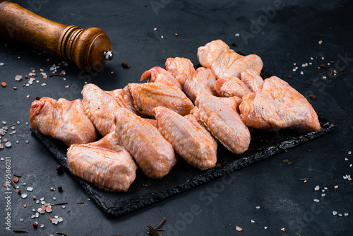 Obraz na płótnie Raw marinated barbecue chicken wings in sauce and spices on a dark background. w salonie