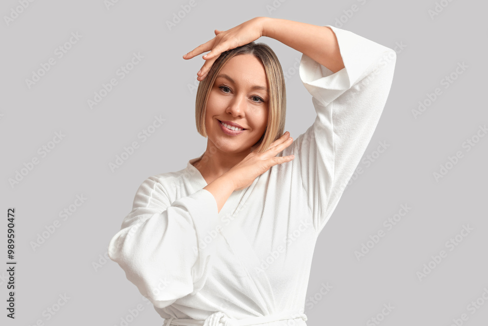 Portrait of beautiful mature woman in bathrobe on grey background Portrait of beautiful mature woman in bathrobe on grey background