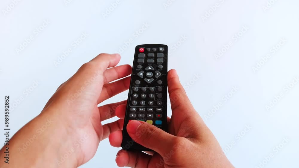 a hand holding a TV remote, with fingers pressing buttons several times a hand holding a TV remote, with fingers pressing buttons several times