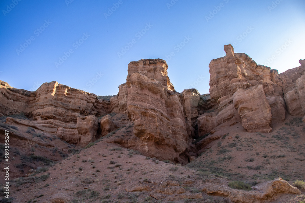 A stunning Charyn canyon in the desert beneath a bright blue sky A stunning Charyn canyon in the desert beneath a bright blue sky