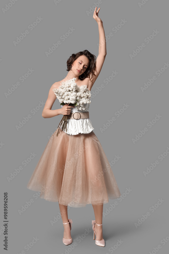 Naklejka premium Beautiful young woman with bouquet of blooming white lilac flowers on grey background
