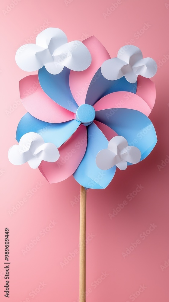 Colorful pink and blue paper pinwheel with white cloud decorations on a pink background Colorful pink and blue paper pinwheel with white cloud decorations on a pink background