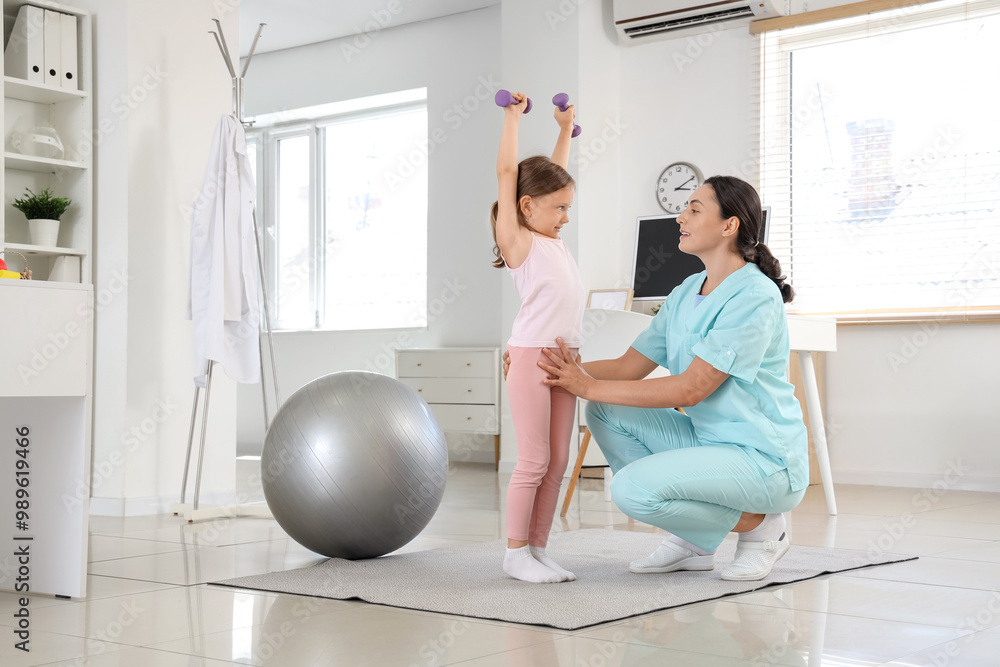 Obraz premium Female osteopath and little patient with dumbbells doing exercises in clinic