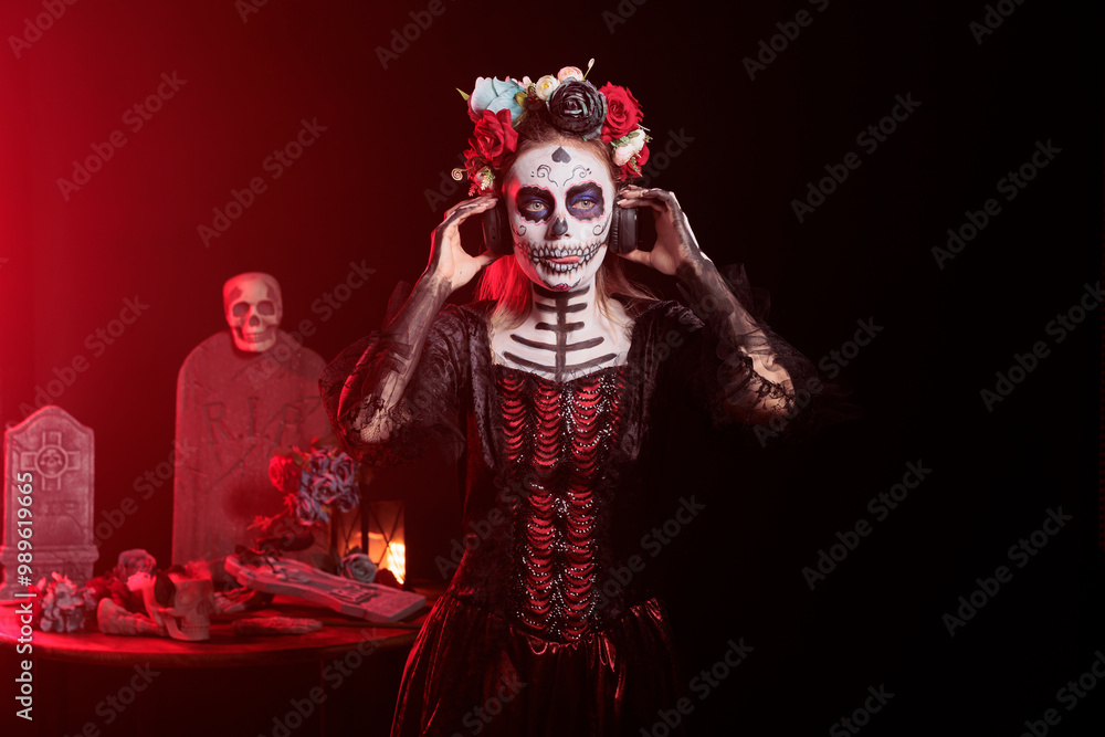 Woman wearing headphones, hearing songs at Day of the Dead event to remember the deceased. Lady listening music during Mexican holiday of remembrance for those who have passed Woman wearing headphones, hearing songs at Day of the Dead event to remember the deceased. Lady listening music during Mexican holiday of remembrance for those who have passed