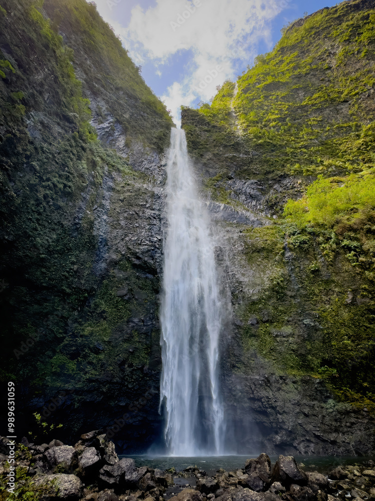 Fototapeta premium Scenic view of Hanakapiai Falls, a waterfall at the end of Hanakapiai Valley hiking trail, Kauai, Hawaii, USA against blue sky with clouds