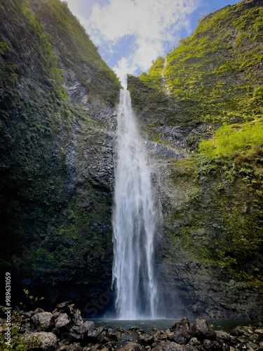 Scenic view of Hanakapiai Falls, a waterfall at the end of Hanakapiai Valley hiking trail, Kauai, Hawaii, USA against blue sky with clouds
