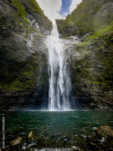Scenic view of Hanakapiai Falls, a waterfall at the end of Hanakapiai Valley hiking trail, Kauai, Hawaii, USA against blue sky with clouds