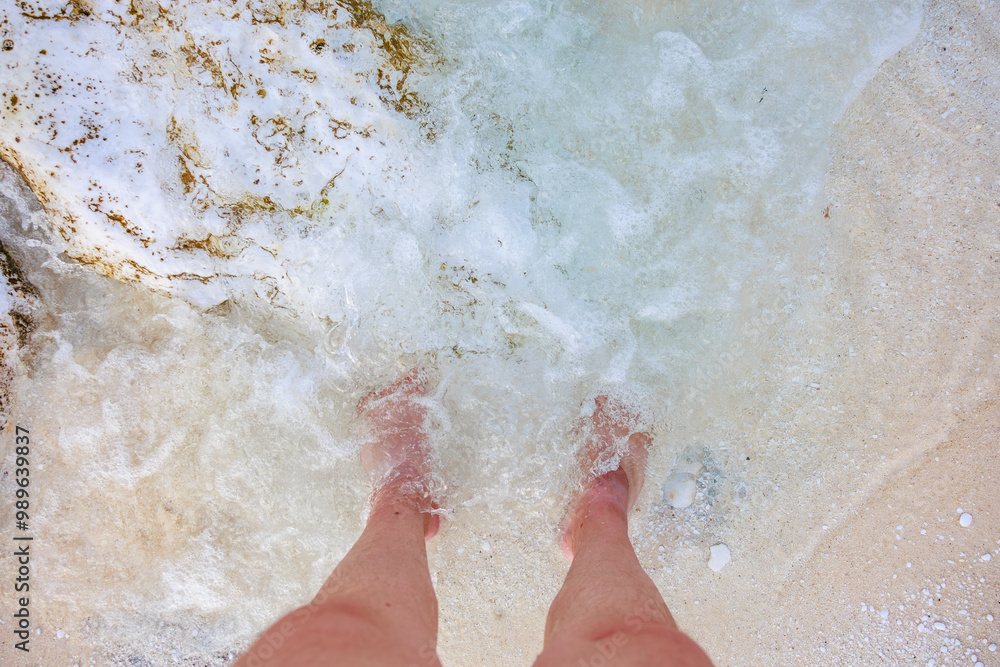 Fototapeta premium A person's feet are in the ocean water