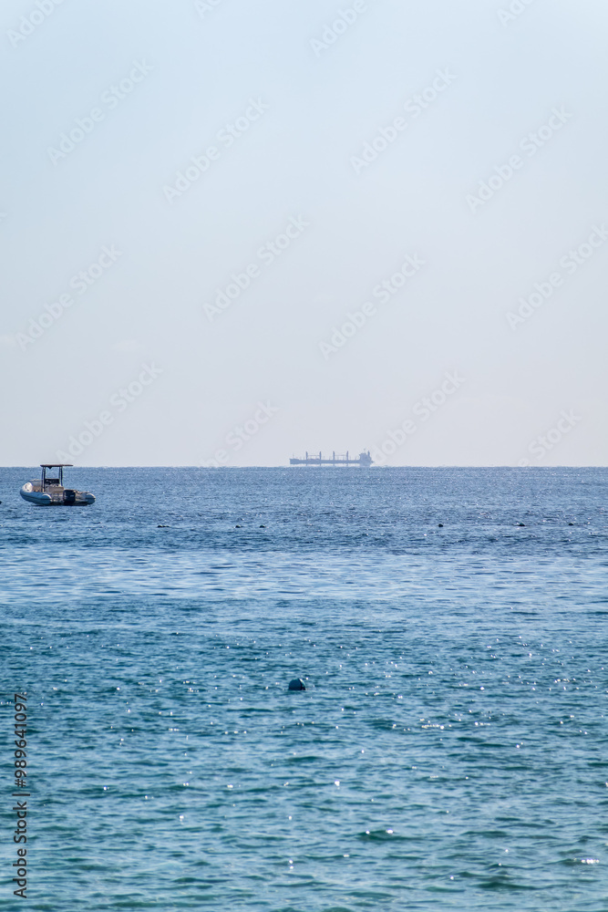 Calm blue sea with the silhouette of a large ship on the horizon Calm blue sea with the silhouette of a large ship on the horizon