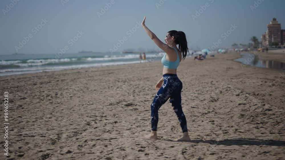 young girl long-haired brunette Caucasian woman walking sideways on the sand of the beach on a sunny day blocking the sunlight by raising her left hand young girl long-haired brunette Caucasian woman walking sideways on the sand of the beach on a sunny day blocking the sunlight by raising her left hand