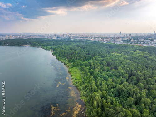 Big lake with green shores in bright sun light and city on horizon, aerial landscape. Recreation concept. Aerial view photo