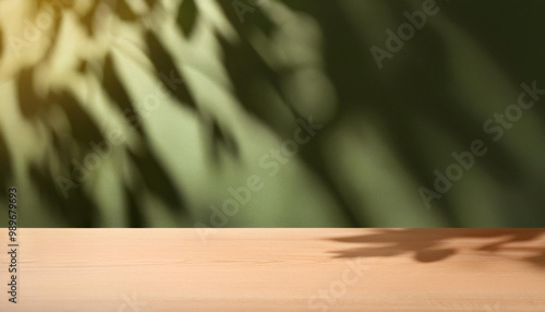 Empty table and darkgreen wall. Table with sun reflections and leaves shadows on beige wall. Background with bokeh for product photo