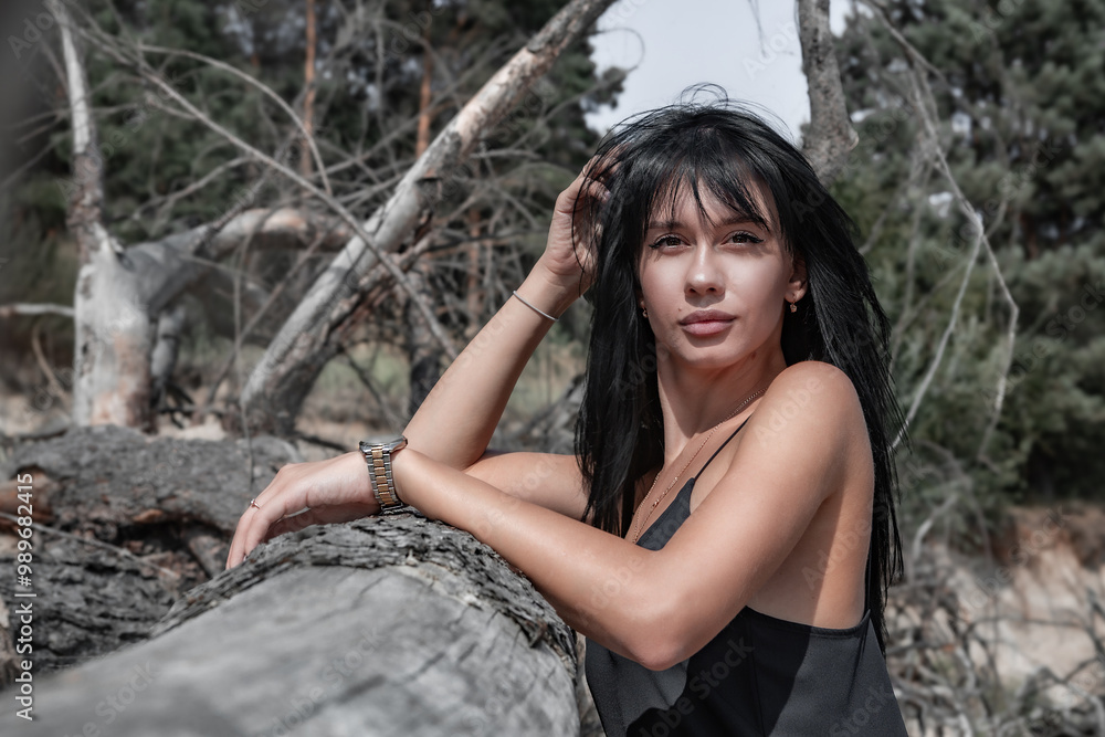Portrait of a young sexy beautiful woman looking into the camera lens against the background of fallen dry branches and trees. Fashion portrait. Portrait of a young sexy beautiful woman looking into the camera lens against the background of fallen dry branches and trees. Fashion portrait.