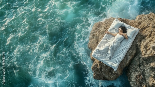 A woman relaxes on a bed placed on a rocky shore as waves crash against the rocks under a bright sunlight near the coast photo