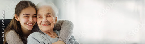 A young woman embraces her grandmother, both smiling and looking happy.